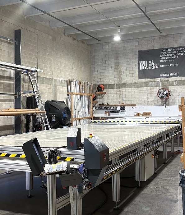 The Shades Factory production floor featuring an automated CNC fabric cutting table used by a custom shades manufacturer for precision fabrication.