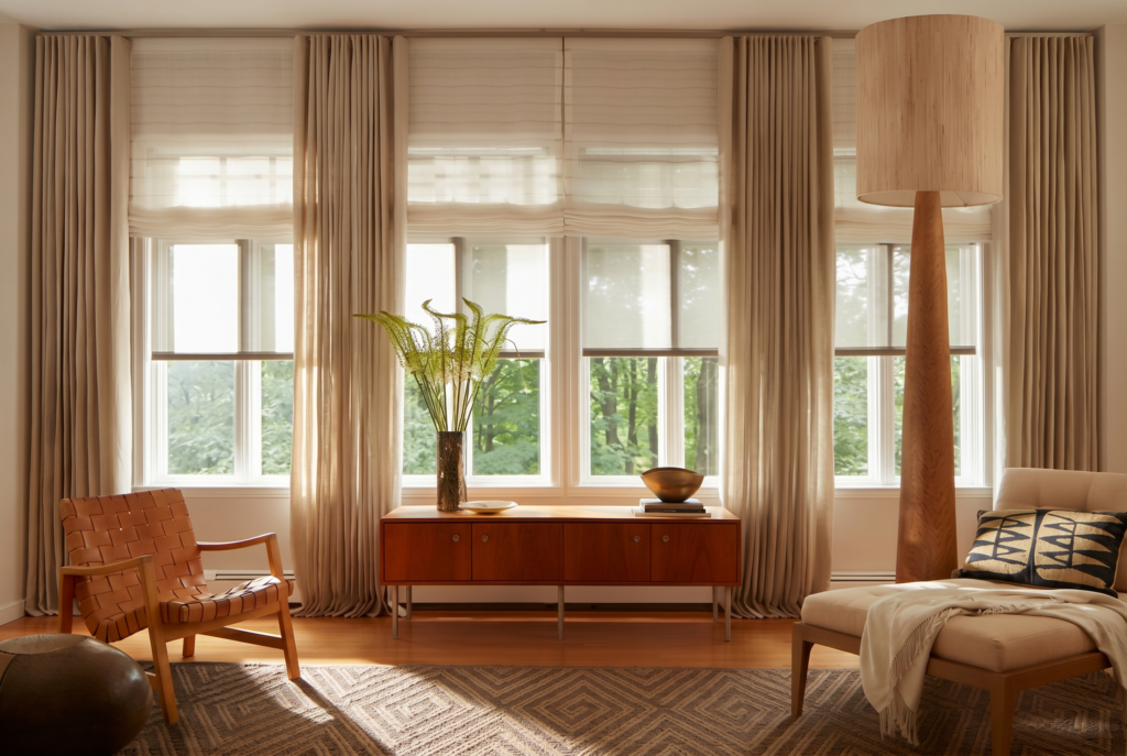 Elegant living room featuring custom blinds and shades with sheer window coverings and ripple fold drapery, creating a warm, light-filled space with timeless style.